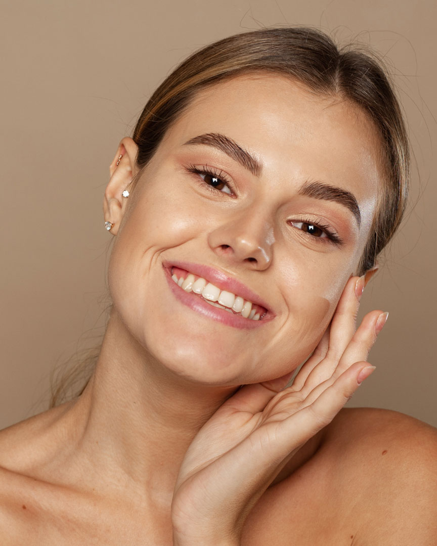 Femme souriante sur fond marron.